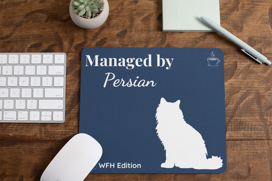 Navy blue mousepad featuring white Persian cat silhouette with "Managed by Persian - WFH Edition" text and coffee cup icon, shown on wooden desk with keyboard, mouse, succulent plant and pen